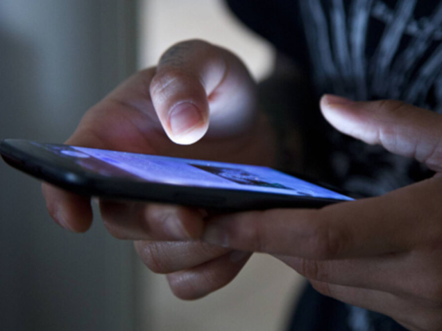 Hands holding smartphone in the dark.